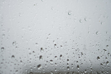 Rainy, autumn weather outside the window. Drops of water on the glass on a blurred background. Romantic grubby topic. Stock photo for design