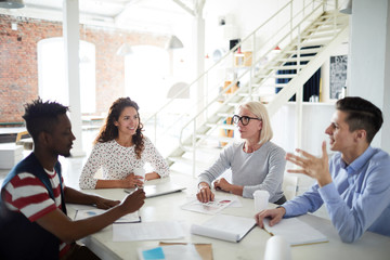Group of business people gathered together at a table discussing an interesting idea at office