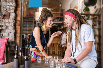 Hippies in bar. Two beaming fashionable hippies enjoying their communication in the bar drinking cocktails