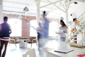 Blurred motion of young business colleagues working in a busy open plan office