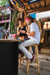 Showing photos. Hippie man with long hair showing some photos on his phone his beautiful stylish girlfriend