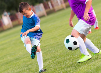 Obraz premium Boy kicking football on the sports field