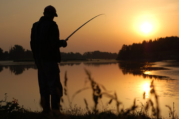 Fisherman with a fishing rod in the morning at dawn