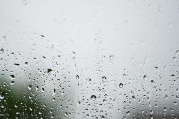 Rainy, autumn weather outside the window. Drops of water on the glass on a blurred background. Romantic grubby topic. Stock photo for design