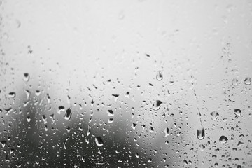 Rainy, autumn weather outside the window. Drops of water on the glass on a blurred background. Romantic grubby topic. Stock photo for design