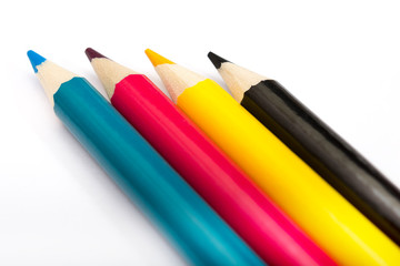 Four colored pencils. The colors cyan, magenta, yellow and black. The concept of polygraphy.