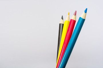 Four colored pencils. The colors cyan, magenta, yellow and black. The concept of polygraphy.
