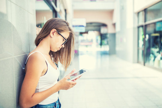 Beautiful young schoolgirl with tablet in the city