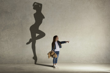 Baby girl dreaming about dancing ballet. Childhood and dream concept. Conceptual image with shadow...