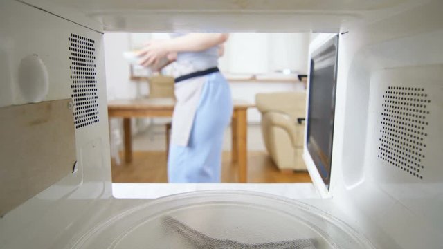 view from microwave oven wife takes out dish with pies