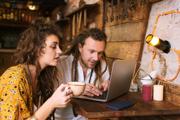 Tea and work. Appealing curly woman drinking tea and watching her handsome man working