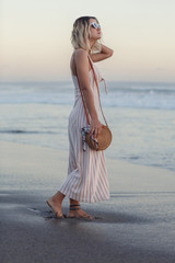 Young beautiful woman wearing sea style clothing on beach. Summer time vacation