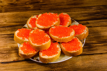 Sandwiches with red caviar on wooden table