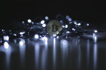 Coin of bitcoin payment system with decentralisation and electronic wallet. Festive atmosphere. Cold white Christmas tree lights in the background. BTC is a cryptocurrency. 4K, Panning, Closeup
