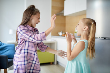 Two youthful ecstatic girls expressing enjoyment of their play and having fun at home