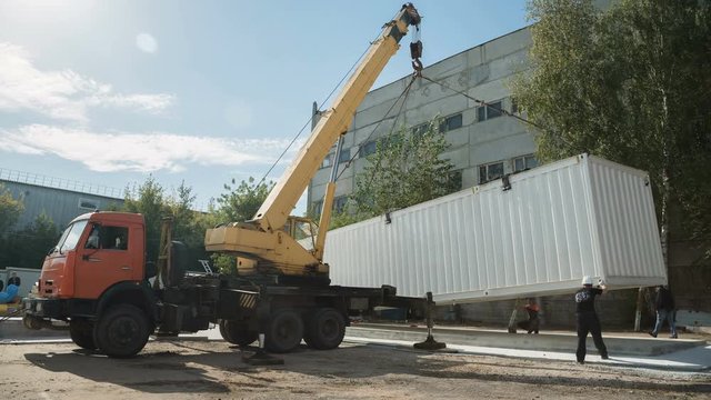 timelapse auto crane transports white container near plant