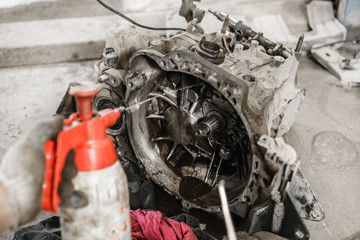 Fototapeta premium rinse clutch unit after the leaking of engine oil. Change and repair clutch, drive axle. working underneath a lifted car. Professional mechanic work maintenance car. Garage car service.