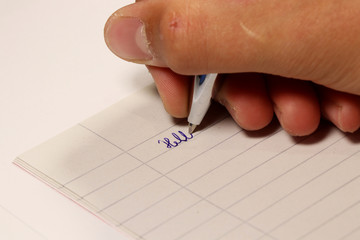 A young boy writing particular word on paper at dictation in school.