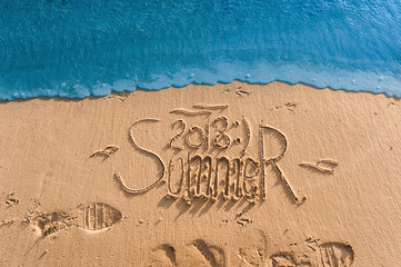 Summer passed the concept. The wave washes away the inscription summer 2018 written on the sand. End of vacation and season.
