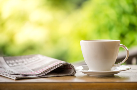 good morning coffee cup with news paper on nature green background in garden