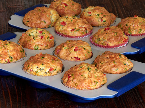 Two trays of savory muffins with cheddar, spinach and red peppers