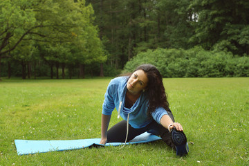 Young beautiful brunette doing stretching in the park on a summer morning