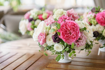 Arrangement of fresh flowers in pastel colors. Wedding background. table in a restaurant. different varieties of garden and shrub roses in a light vase on wooden table