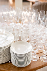 Clean plates, glasses and cutlery on wooden table. Catering set-up ready for the event to begin. ervice area the waiter in restaurant.