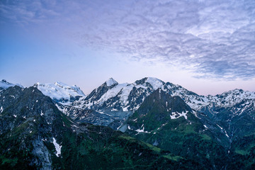Obraz premium Scenic view of beautiful landscape in Swiss Alps. Fresh green meadows and snow-capped mountain tops in the background in springtime, Switzerland.