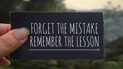 Motivational and inspirational quote - ‘Forget the mistake, remember the lesson’ written on a black paper. Vintage styled background.