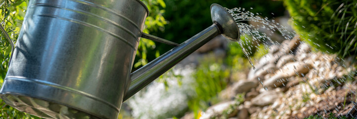 Watering flowerbed using watering can. Gardening hobby concept banner. © andreaobzerova