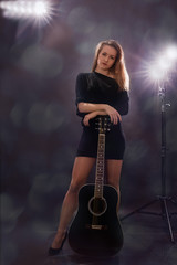 Fototapeta na wymiar Beautiful girl with guitar on black background.