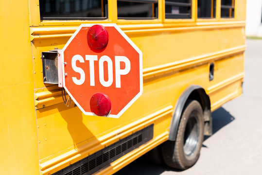 cropped shot of traditional school bus with stop road sign