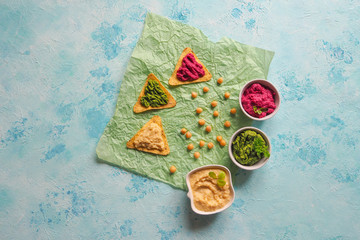 Traditional hummus smeared on corn chips on a blue table. Appetizer of hummus.