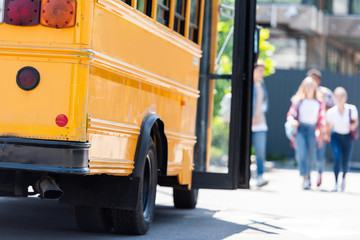 traditional american school bus with group of students walking blurred on background