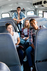 group of smiling teen scholars riding school bus and looking at camera © LIGHTFIELD STUDIOS