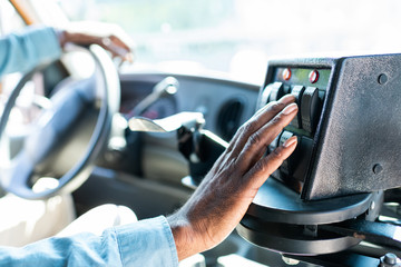 cropped shot of african american bus driver pushing buttons on panel at bus