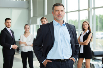 Mature smiling business manager crossing his arms in front of his business team.