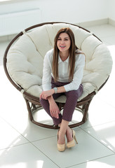 dreaming young woman sitting in a soft round chair
