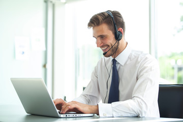 Happy young male customer support executive working in office.