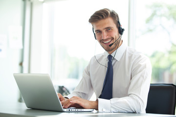 Happy young male customer support executive working in office.