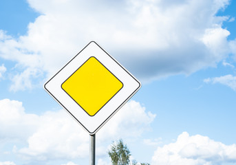 Road sign main road traffic priority against blue sky background