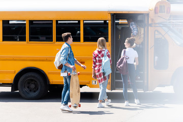 group of teen students walking inside of school bus