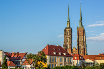 Naklejka premium medieval old city street view with red roofs of small house and gothic tower of catholic church on blue sky background in colorful summer bright contrast day time