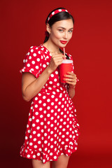 cheerful brunette pin-up girl holding soft drink