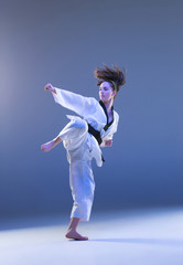 The karate girl with black belt jumping on blue background