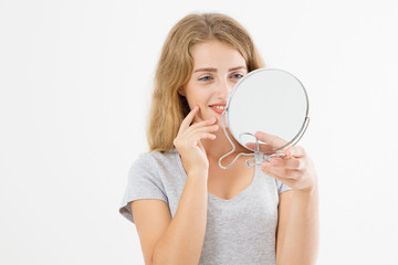 Young caucasian blonde woman looking wrinkles on face in mirror isolated on white background. Skin care and makeup concept. Copy space