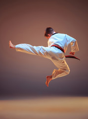 Young boy training karate and jumping on blue studio background © master1305