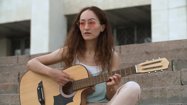 Woman playing acoustic guitar on the stairs