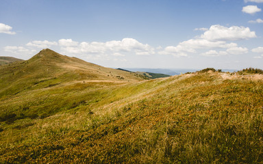 Scenic view of grassland mountain hills during sunny day